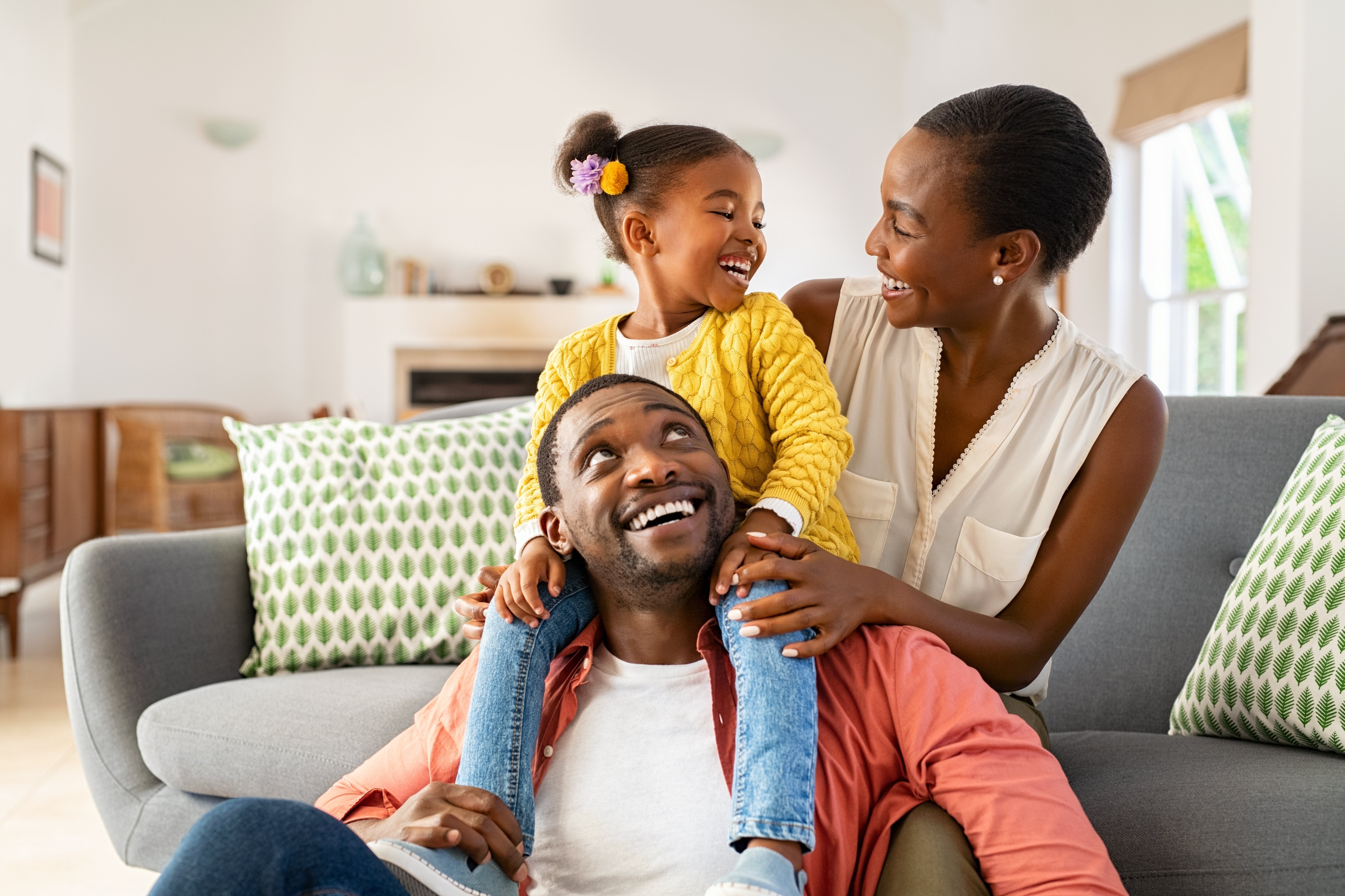 family-of-three-1 image of a mother, father and daughter sitting on the couch playing