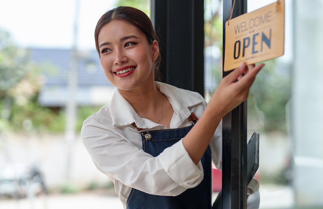 small business owner smiling while flipping over the open sign